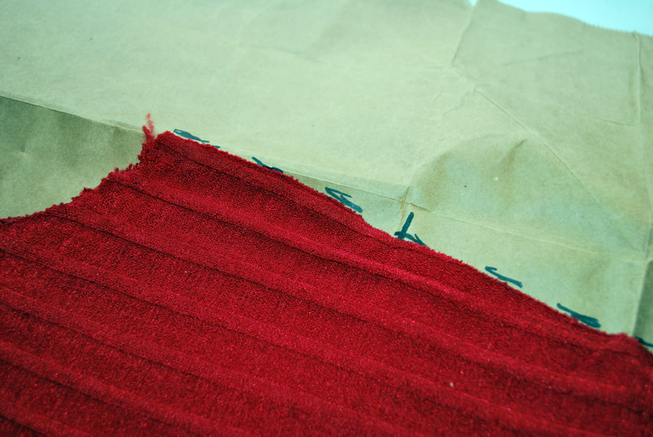 Tracing around the outside of the armhole and side seam of the red top. Cross marks are used to mark the shoulder seam and under bust lines.