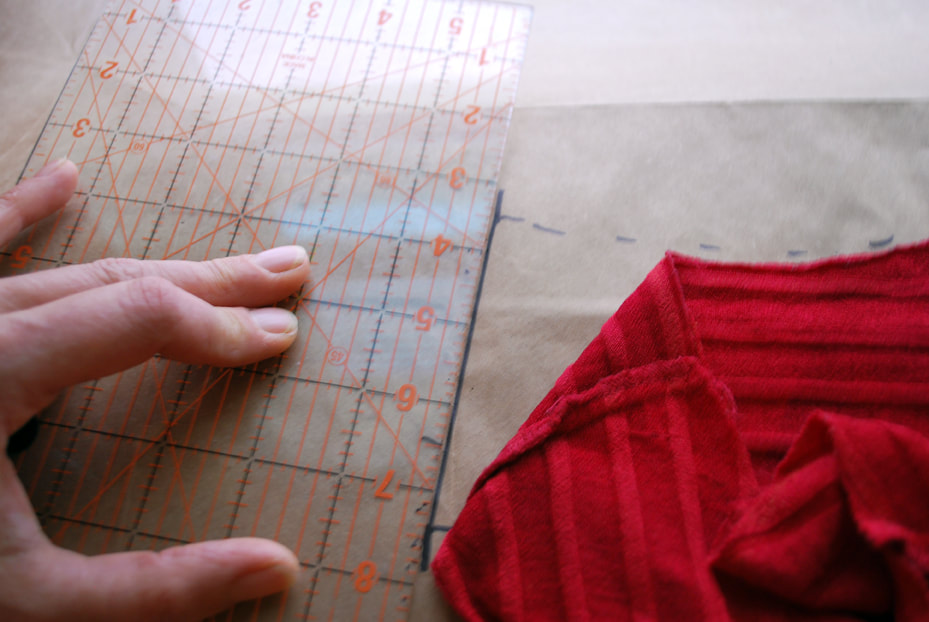 Using a ruler as a guide to draw the shoulder seam line on the pattern paper.