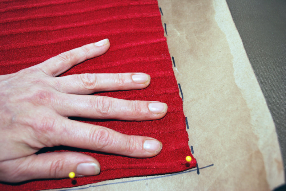 A hand holds the bottom of the panel to keep it smooth, and the other hand traces dotted lines around the bottom edge.
