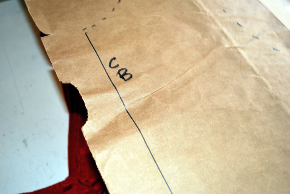 A brown paper pattern with the letters CB near a straight line at center back.