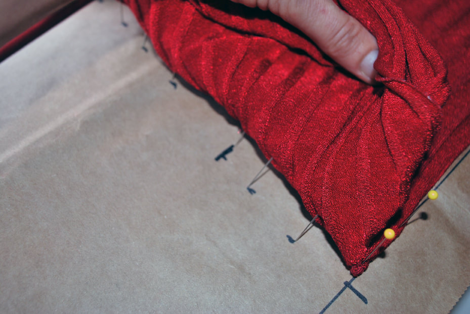 Pulling the bust fabric back down to clearly mark the overlap on the pattern with a cross mark.