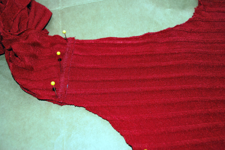 Pinning the shoulder seam of the red top through to the paper underneath.