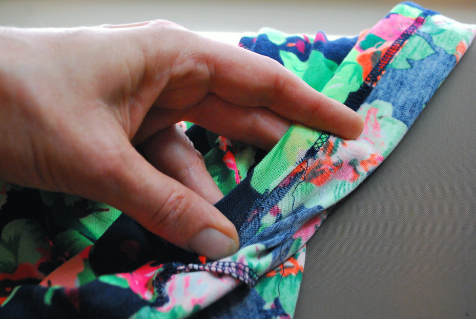 Pulling on the hem to stretch it out and help the threads pull apart more easily.