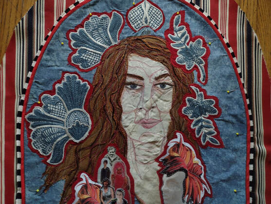 Fabric portrait of an older woman with brown hair crowned with blue and white floral embroidery