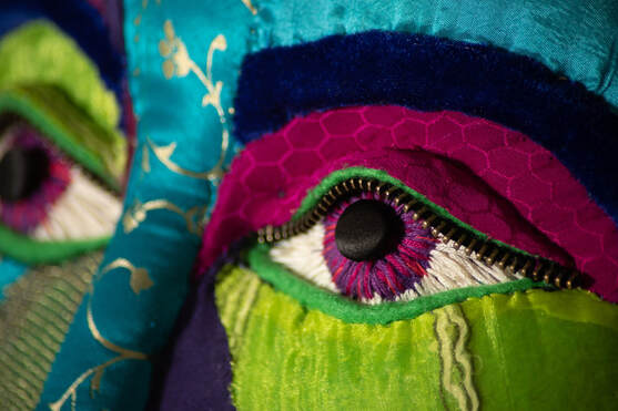 Closeup of a multi-colored fabric face with embroidered eyes