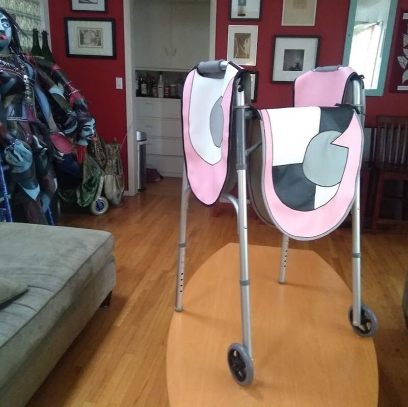 A classic aluminum walker with vinyl hangings in a graphic pink, white, black, and grey graphic design.