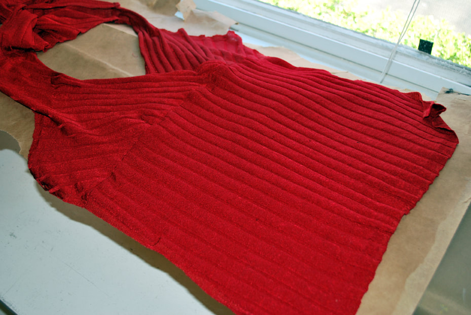 Front of red knit top laid out onto brown pattern paper. This front has 3 pieces: 2 bust pieces and a tummy panel.