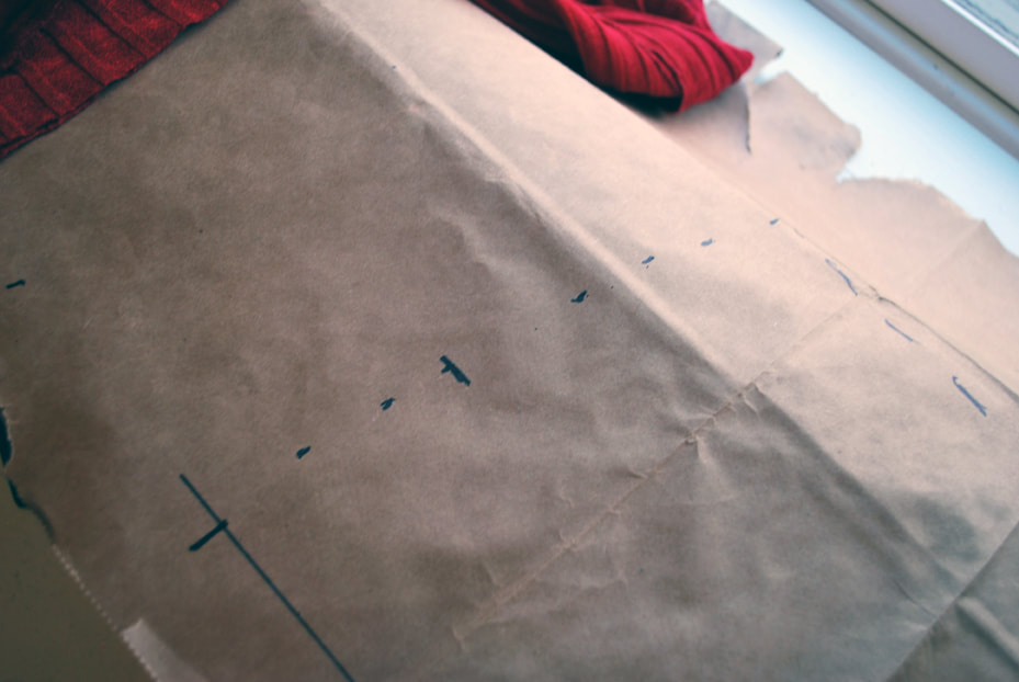 Pattern partially drawn out on brown paper of the top of the tummy panel, with a cross mark to note where the bust panels overlap.