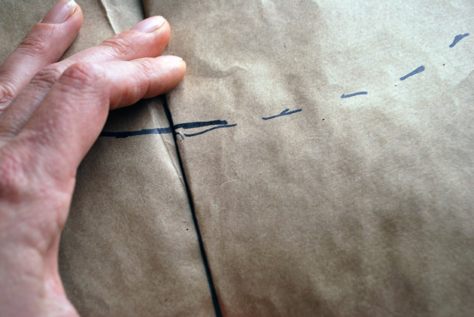Drawing a line extending across the folded edge to correct the shoulder seam pattern and make them both match. 