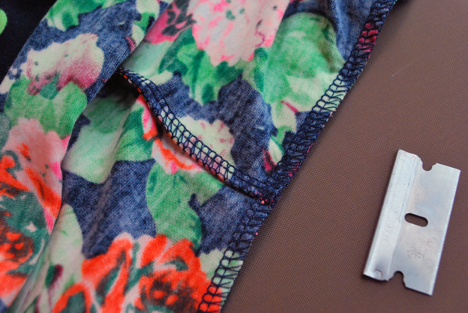 Closeup of the inside of a brightly colored dress sewn together with a 4-thread overlocked seam. On the right is a safety blade.