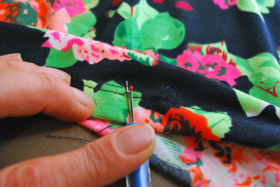 Using a seam ripper to cut the straight stitches on the outside of a coverstitched hem.