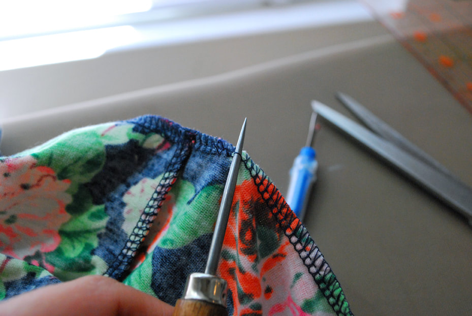 An awl pulls at the straight stitches at the base of a 4-thread overlocked seam.