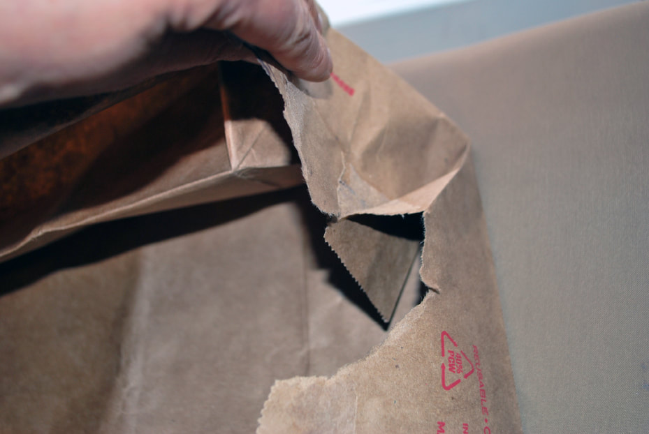 Continuing to pull the seams apart until the paper bag can lay flat