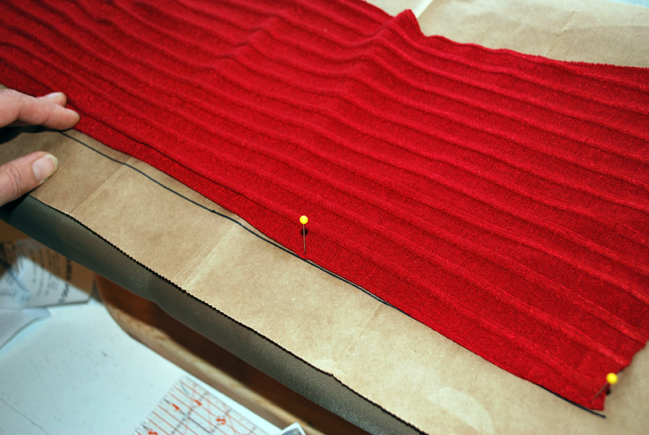 Lining up the folded edge of the red top's center back with the drawn-in straight line.
