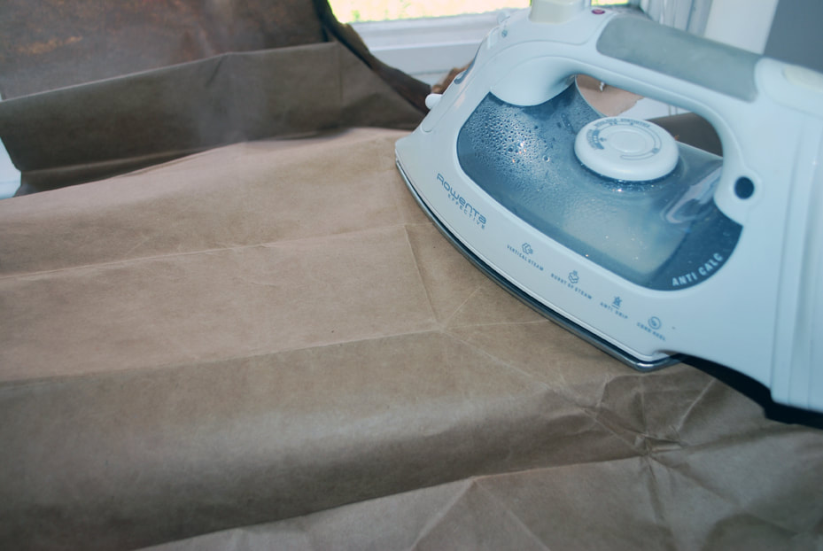 Using an iron to get the creases out of the now flattened paper bag