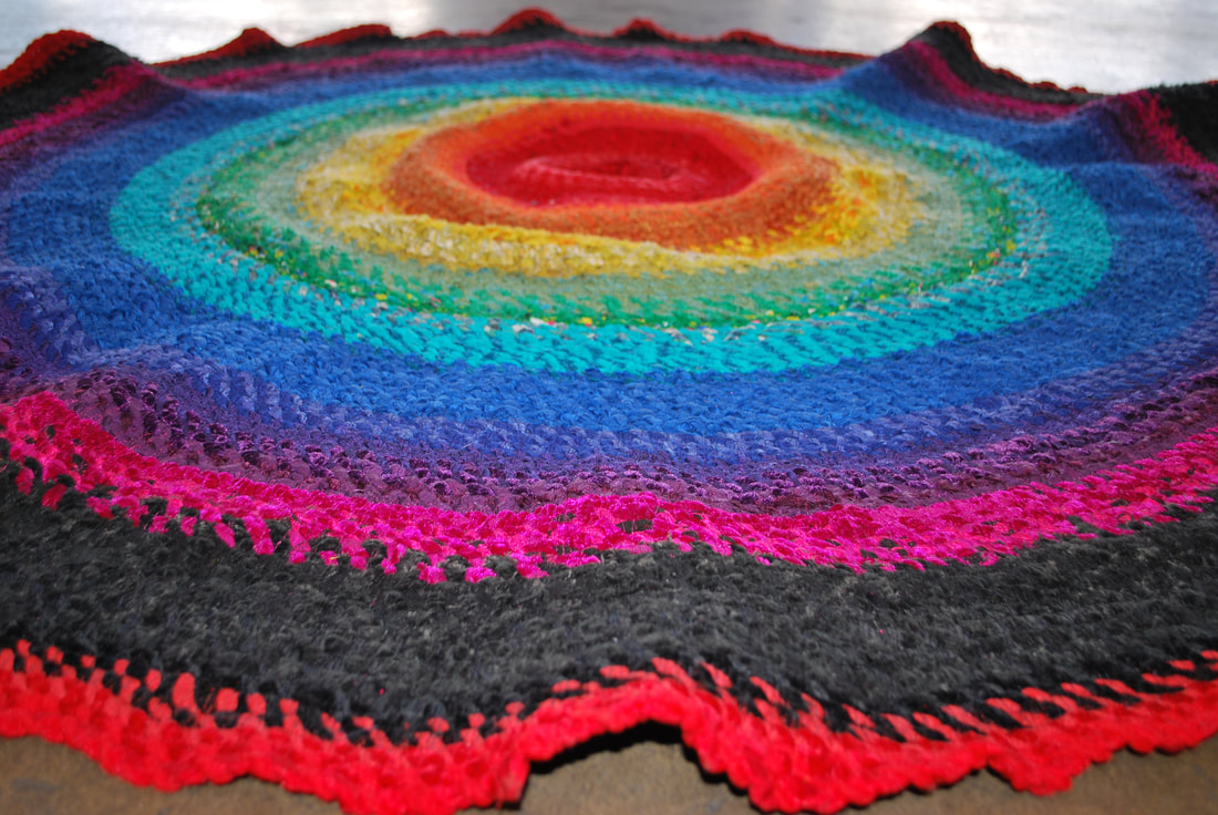 A rippling circular rag rug in rainbow colors
