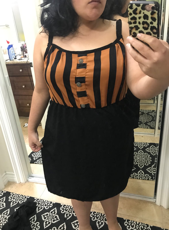 A dark-haired woman models a dress with an orange and black striped top and a black skirt.