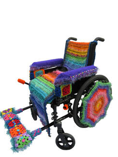 A manual wheelchair covered in colorful crocheted yarn